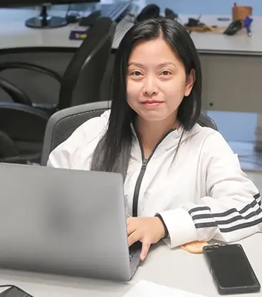 An access programmer discusses a client's access database on a laptop to streamline operations by customized programming.