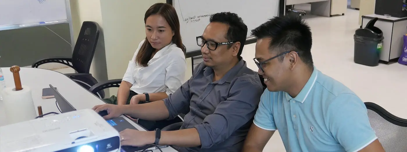 Cambria software employees beaming as they review code together, showing quality developers in the Philippines.